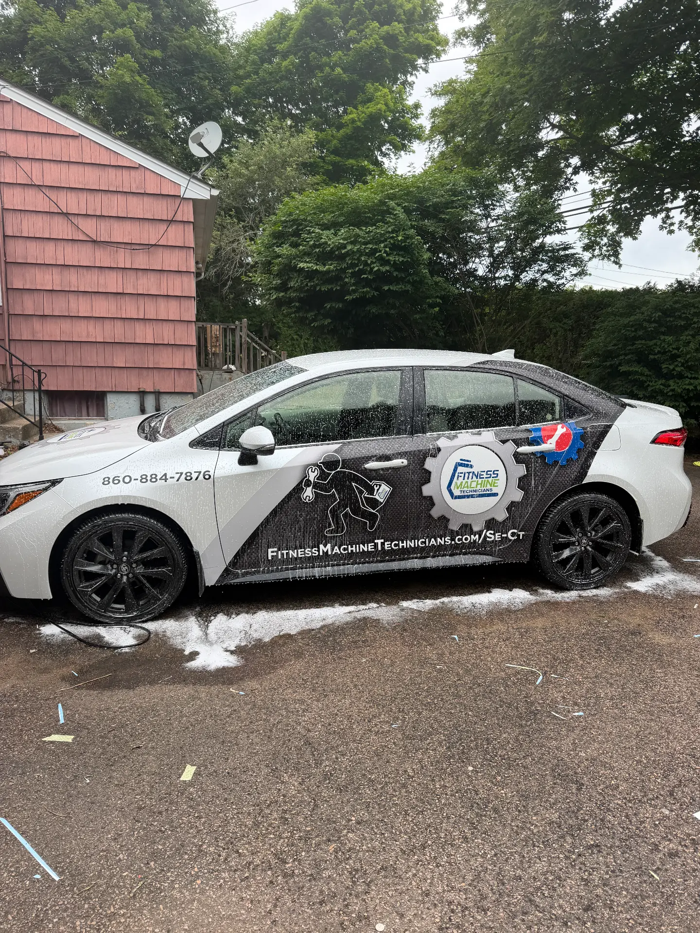 Toyota Corolla wrapped in a custom black and white printed commercial design with Fitness Machine Technicians branding